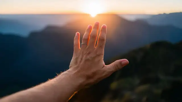 A hand reaching out to the sun, symbolizing hope and connection in Biblical Metaphors of divine guidance and light.