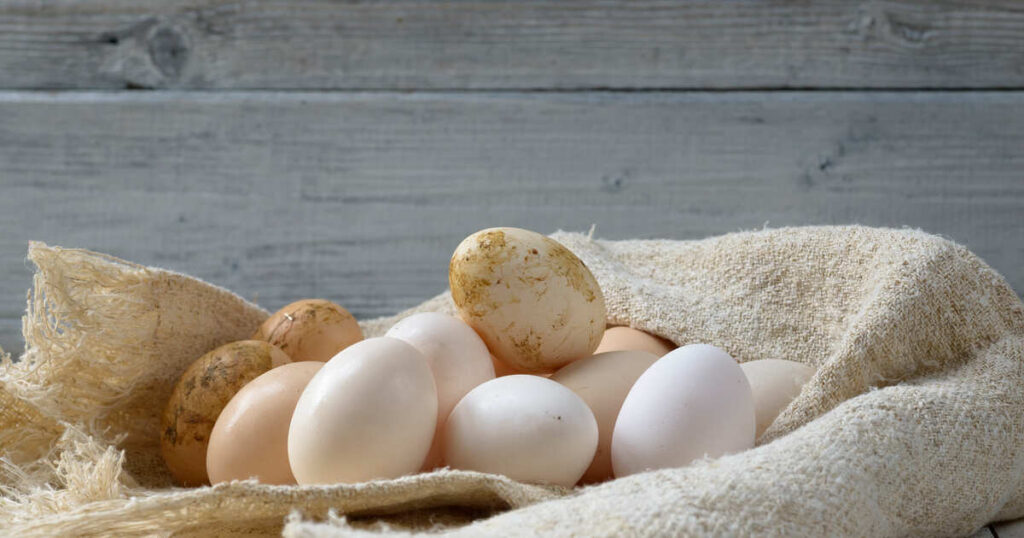 A sack filled with eggs rests on a wooden table, symbolizing the Biblical Meanings of Eggs in various interpretations.