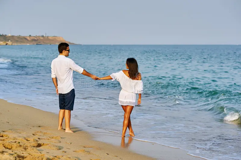 A man and woman holding hands on the beach, symbolizing trust amidst the question, "What Are Dreams About Cheating?