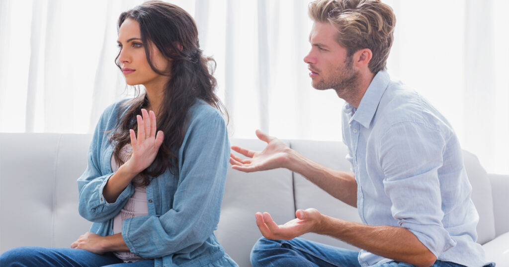 A man and woman sit on a couch, engaged in conversation about how to interpret your dreams about cheating.