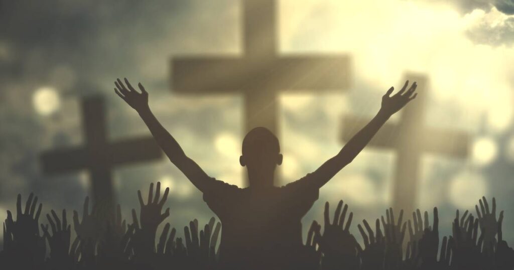 A person with hands raised in prayer before a cross, embodying Wednesday Morning Prayers for Trust in God.