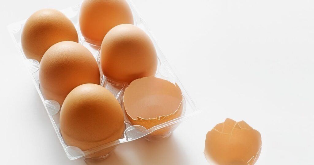 A plastic container holding Double Yolk Eggs placed on a clean white surface, showcasing their unique appearance.